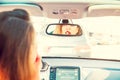 Back view young woman looking in rear view mirror and putting make up in car. Modern busy life. beautiful girl sitting in drivers Royalty Free Stock Photo