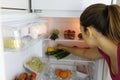 Back view of young woman searching for heathy food in the fridge Royalty Free Stock Photo