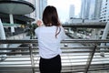 Back view of young woman standing and looking far away in urban city background. Royalty Free Stock Photo