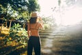 Back view of young woman in straw hat rwalking up stairs in green tropical park in sun light Royalty Free Stock Photo