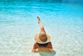 Back view of young woman in straw hat and white bikini relax in turquoise sea on tropical paradise beach Royalty Free Stock Photo