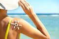 Back view of young woman tanning at the beach with sunscreen cream in sun shape on her shoulder. UV sunburn protection and Royalty Free Stock Photo