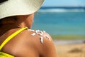 Back view of young woman tanning at the beach with sunscreen cream in sun shape on her shoulder. UV sunburn protection and Royalty Free Stock Photo