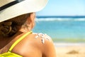 Back view of young woman tanning at the beach with sunscreen cream in sun shape on her shoulder. UV sunburn protection and Royalty Free Stock Photo