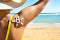 Back view of young woman tanning at the beach with sunscreen cream in sun shape on her shoulder. UV sunburn protection and Royalty Free Stock Photo