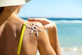 Back view of young woman tanning at the beach with sunscreen cream in sun shape on her shoulder. UV sunburn protection and Royalty Free Stock Photo