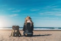 Back view. Young woman tourist in hat and with backpack sitting on beach and looking at sea, on coastline, on horizon. Royalty Free Stock Photo