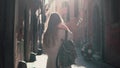Back view of young woman walking at city street in Europe at morning. Girl exploring the old town alone, looking around. Royalty Free Stock Photo
