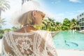 Back view of young woman wearing summer hat relaxing in luxury hotel at sunny summer day. Traveler. Tourism