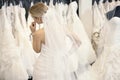 Back view of a young woman in wedding dress looking at bridal gowns on display in boutique Royalty Free Stock Photo