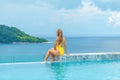 Beautiful young woman in swimwear relaxes in infinity pool at a luxury spa resort Royalty Free Stock Photo