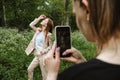 Back view of Young woman holding cell phone and making photo of her girl friend. Two girlfriends take pictures of each Royalty Free Stock Photo