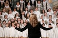 Back of a woman conducting a choir of children
