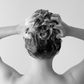 Back of a woman in a shower shampooing her hair, massaging her head full of suds in black and white. Royalty Free Stock Photo