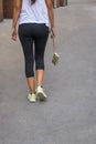 Back of a woman walking holding a hanging pocketbook in yoga pan