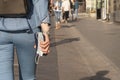 Back of woman wearing blue clothing, black backpack and wristwatch and hand holding mask and mobile. City street in background