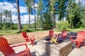 Back yard with fire pit and red chairs near newly bild luxury real estate home with forest biew and green grass Royalty Free Stock Photo