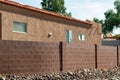 Back yard wall with red bricks and rock garden near sidewalk with orange stucco cement house with adobe roof tiles Royalty Free Stock Photo