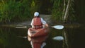 Back young adult woman paddling kayaking canoe on a lake on summer day Royalty Free Stock Photo