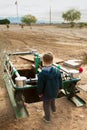 Young Boy Looks Down Into An Open Grave At A Dusty Desert Cemetery