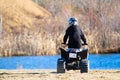 The back of a young boy on a quad with a blue pond in the background