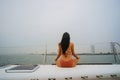 Young healthy and calm woman doing yoga meditation and sitting with lotus pose on sailing yacht boat