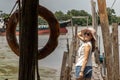 The back of a young woman in casual clothes standing on an old wooden pier and looking at the view River Royalty Free Stock Photo