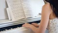 Back of young woman playing the piano in bright room, hand held