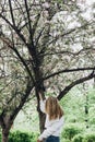 Back of a young woman in spring park. Spring day. Sakura. Summer vacation. Lifestyle