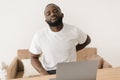 Backache. African american man suffering from low back pain from strenuous work on laptop while sitting at workplace in Royalty Free Stock Photo