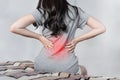 Backache and Lower back pain concept. Young woman suffering from back pain, on bed after waking up Royalty Free Stock Photo