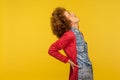 Backache. Portrait of unhealthy woman with curly hair screaming in acute pain and holding sore back Royalty Free Stock Photo