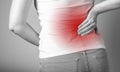 Backache. Woman holding painful lower back with red point closeup. Sport, household injury, chronic diseases. Office Royalty Free Stock Photo