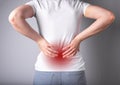 Backache. Woman suffering from lower back pain with red point closeup. Sport, household injury, chronic diseases Royalty Free Stock Photo