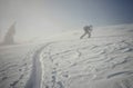 Backcountry skier pushing through the fog on a snowy slope