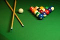 Backdrop of pyramid of pool balls and billiard cues on green billiard table