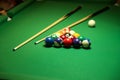 Backdrop of pyramid of pool balls and billiard cues on green billiard table