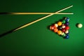 Backdrop of pyramid of pool balls and billiard cues on green billiard table