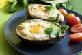 Backed avocado with egg and tomatoes on green background Royalty Free Stock Photo