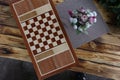 Backgammon board game atop a wooden table adorned with beautiful flowers