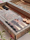 Wooden backgammon board game of pearl inlaid on brown background.