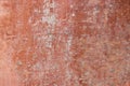 Damaged dark red with underlying white and pink shades smooth stucco wall