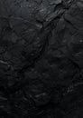 Dark, textured rock surface featuring an uneven, jagged pattern with visible cracks and crevices Royalty Free Stock Photo