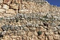 Background of ancient Greek rock wall with vegetation and moss growing between some rocks and a corner of blue sky showing Royalty Free Stock Photo