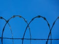 Background of a barbwire fence against a blue sky forming a geometric pattern of archs horizontal Royalty Free Stock Photo