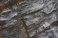 Background on the basis of the texture of rock. Black and brown stone with sloping layers and cracks Royalty Free Stock Photo