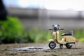 Miniature cream coloured vintage motorcycle toy parking on rock