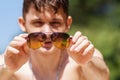 Background, blur, out of focus, bokeh. Portrait of a cheerful guy relaxing and having fun on a Sunny beach. Sunglasses in hand. Royalty Free Stock Photo