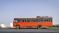 Background blur, pan image of non air-conditioned red intercity bus in Maharashtra, speeding on the street