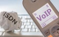 Crumpled paper with the inscription ISDN and modern telephone with VoIP in the display as a sign of the change from ISDN to Voice Royalty Free Stock Photo